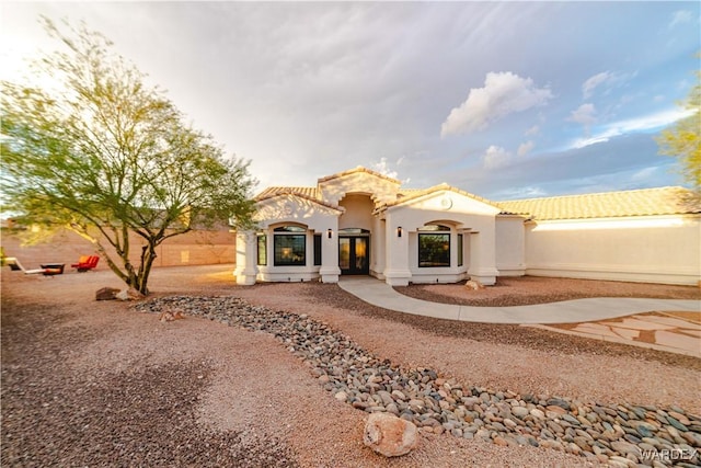 view of front facade with a tile roof, driveway, and stucco siding