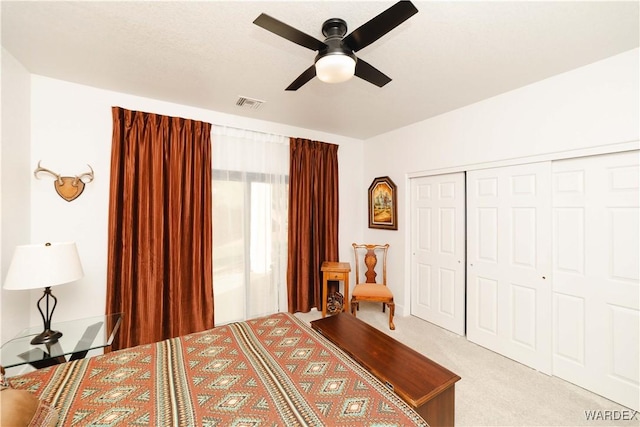 bedroom featuring ceiling fan, a closet, visible vents, and light colored carpet