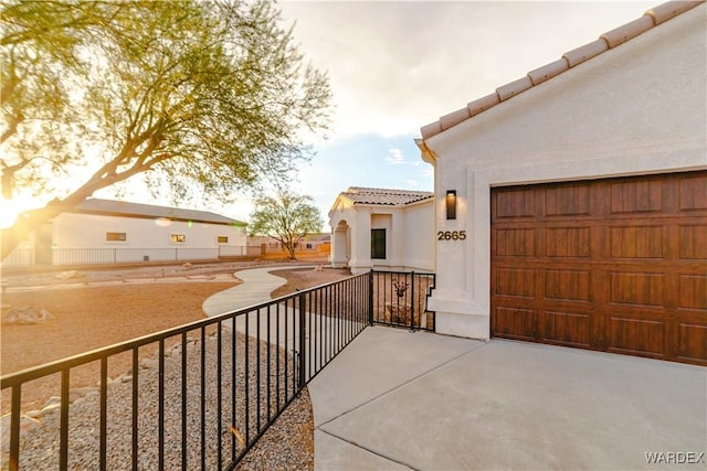 exterior space with a garage, a tiled roof, and stucco siding