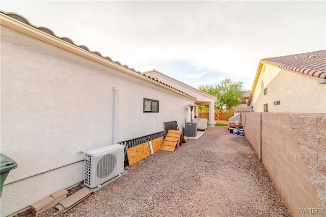 view of property exterior with central AC, a tile roof, fence, stucco siding, and ac unit