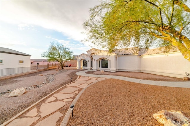 exterior space with stucco siding, a fenced backyard, and a tiled roof