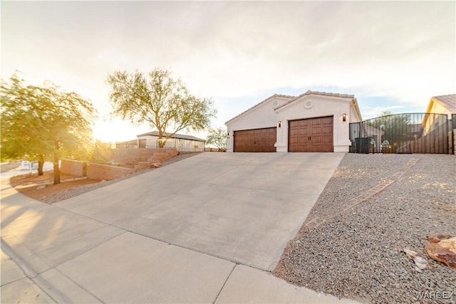 exterior space with stucco siding, an attached garage, a gate, driveway, and a tiled roof