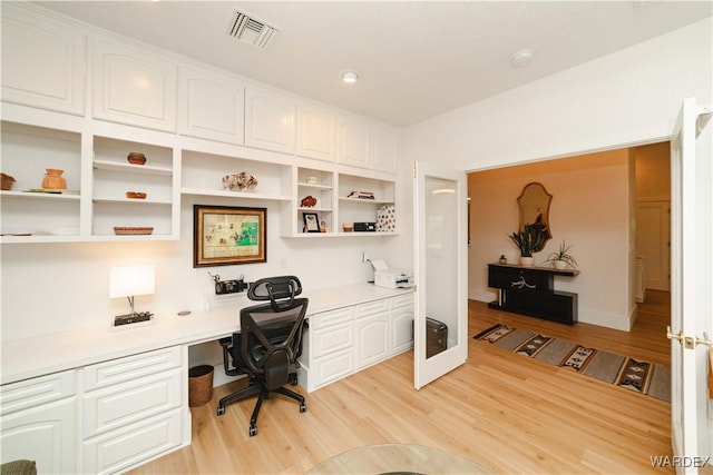 office area with light wood-type flooring, built in study area, and visible vents