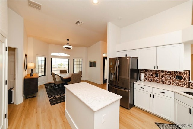 kitchen featuring visible vents, white cabinets, stainless steel fridge with ice dispenser, a center island, and light countertops