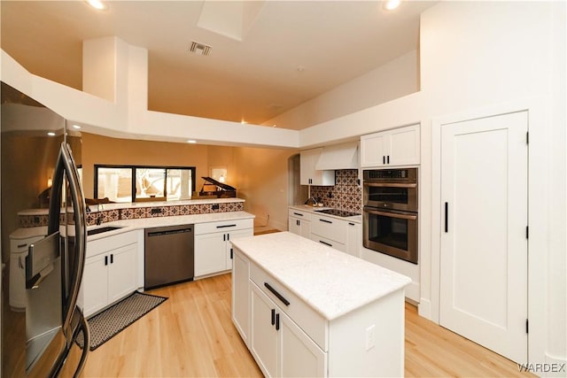 kitchen with a kitchen island, visible vents, white cabinets, light countertops, and black appliances