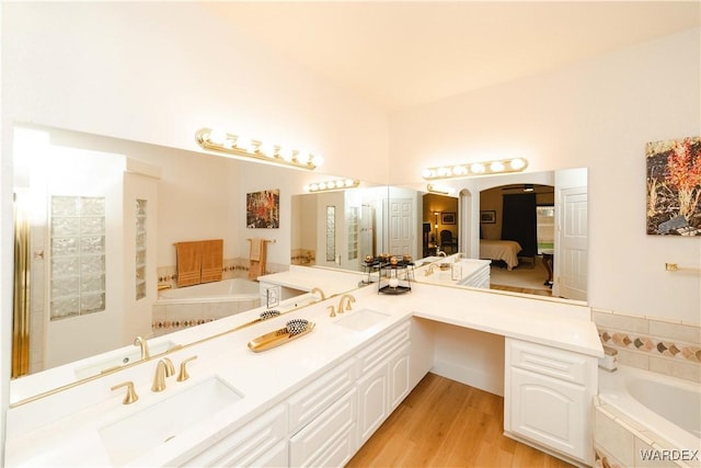 ensuite bathroom featuring a bath, connected bathroom, and a sink