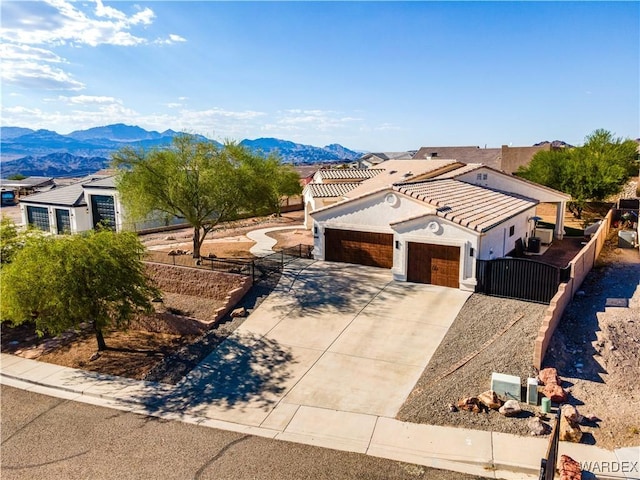 view of front of property featuring a mountain view, fence, a garage, driveway, and a tiled roof