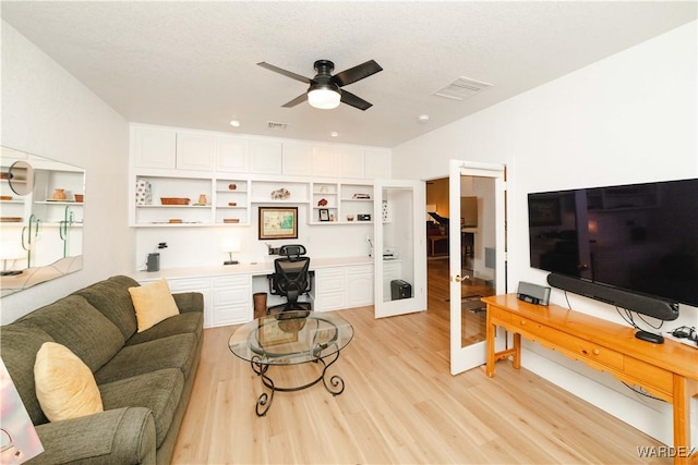 living area featuring a ceiling fan, visible vents, built in desk, and light wood finished floors