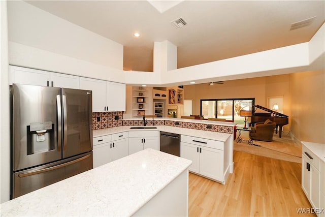 kitchen featuring black dishwasher, white cabinets, a peninsula, stainless steel refrigerator with ice dispenser, and a sink