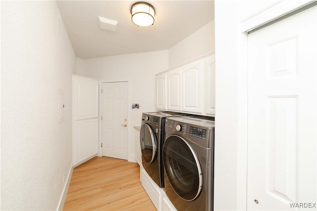 clothes washing area with separate washer and dryer, light wood-style flooring, cabinet space, and baseboards