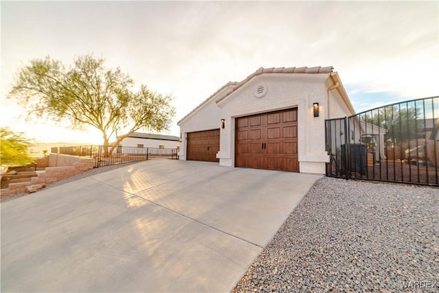 view of property exterior with driveway, fence, a tiled roof, and stucco siding