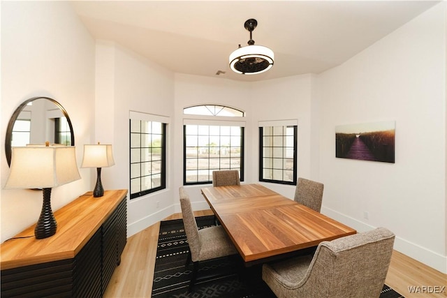 dining space with light wood-style flooring, visible vents, and baseboards