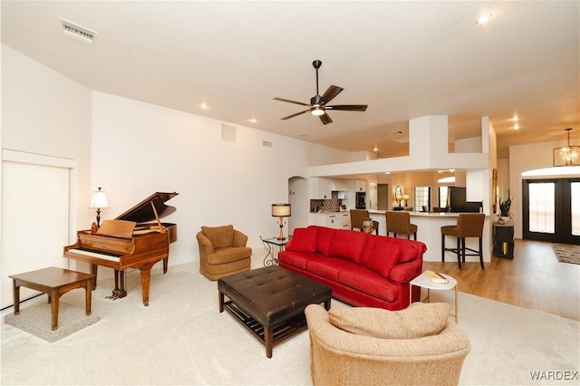 living area featuring arched walkways, ceiling fan, light wood-style flooring, recessed lighting, and visible vents