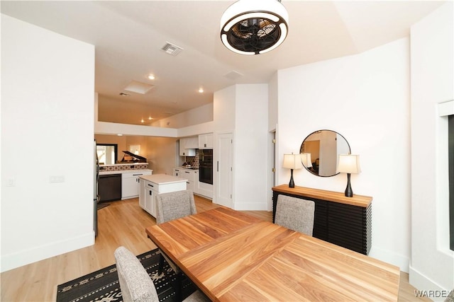 dining space featuring light wood-type flooring, visible vents, and baseboards