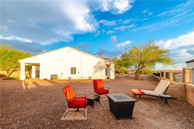 back of property with stucco siding, a fire pit, and a patio