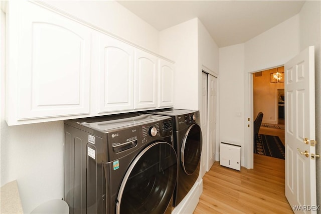 laundry area featuring light wood-type flooring, cabinet space, and washing machine and clothes dryer