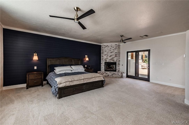 bedroom with a textured ceiling, light carpet, access to exterior, ornamental molding, and a glass covered fireplace