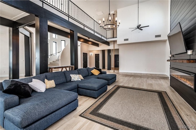 living area featuring light wood finished floors, stairway, a glass covered fireplace, and visible vents