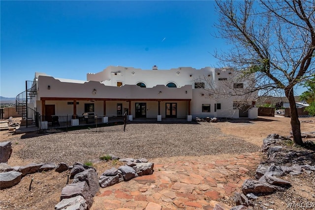 rear view of house with a patio, stairway, and stucco siding