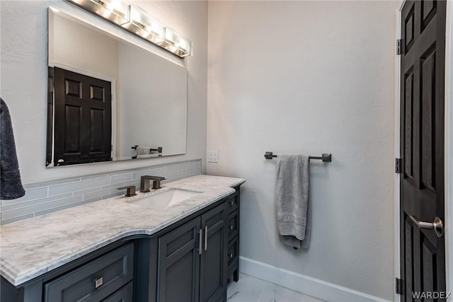 bathroom featuring marble finish floor, baseboards, decorative backsplash, and vanity