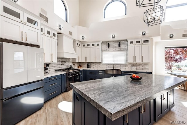 kitchen featuring glass insert cabinets, freestanding refrigerator, white cabinets, and a kitchen island