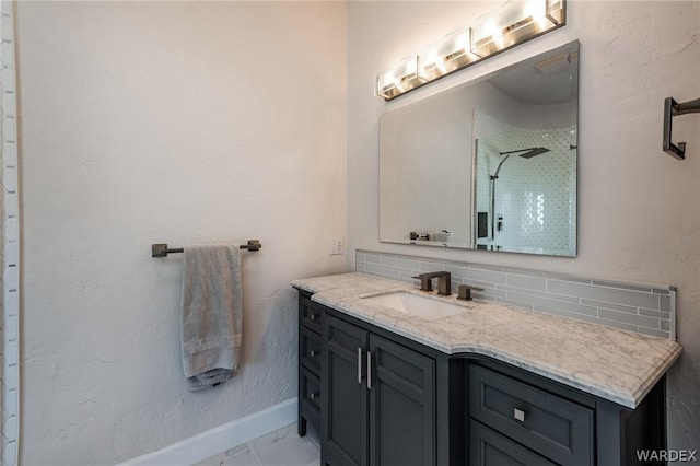 bathroom featuring marble finish floor, baseboards, vanity, and decorative backsplash