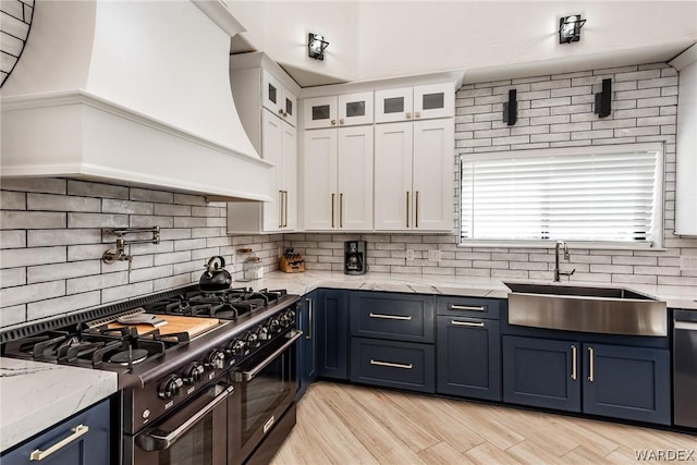kitchen featuring range with two ovens, custom range hood, glass insert cabinets, white cabinets, and a sink