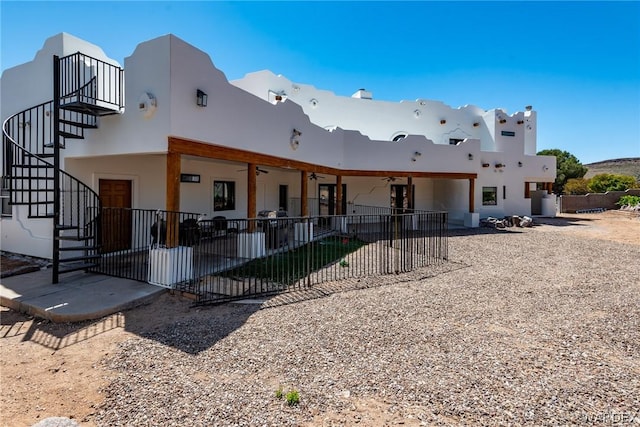 view of front facade featuring fence, ceiling fan, stairway, and a patio