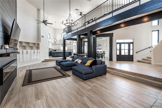 living area with stairs, a high ceiling, plenty of natural light, and light wood-style floors