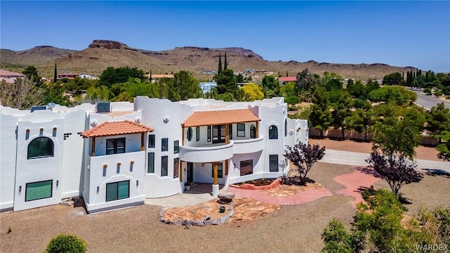 adobe home with a mountain view, a tiled roof, and stucco siding