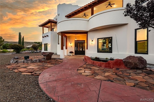 property entrance featuring a tiled roof, ceiling fan, and stucco siding