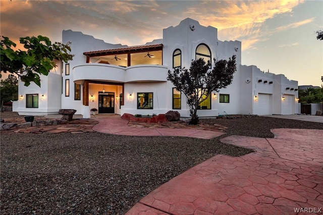 rear view of house with a balcony, a patio area, and stucco siding