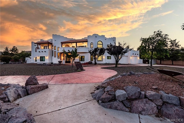 view of front of home featuring a balcony, driveway, and stucco siding