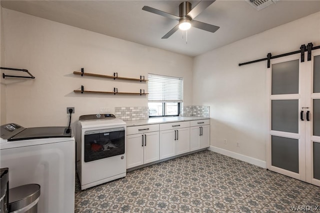 laundry room featuring cabinet space, a barn door, visible vents, a ceiling fan, and independent washer and dryer