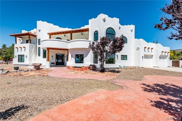 rear view of property featuring a garage, a balcony, and stucco siding