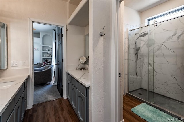 bathroom featuring a marble finish shower, wood finished floors, and vanity