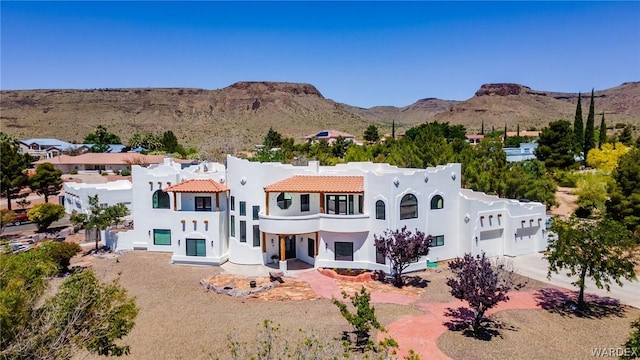 rear view of house featuring a tile roof, a mountain view, and stucco siding