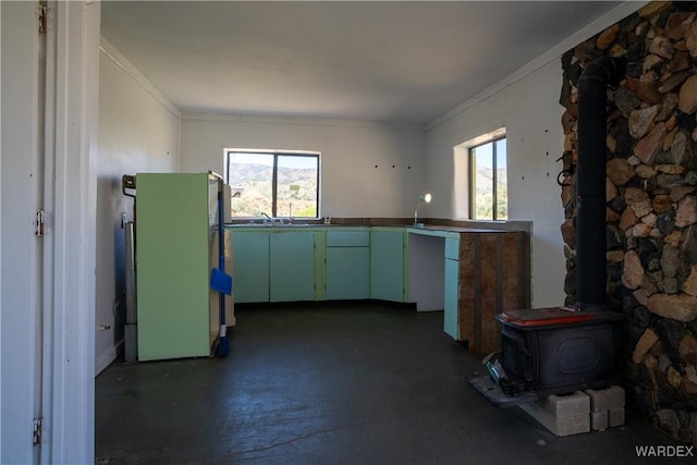 kitchen with ornamental molding, a wood stove, a wealth of natural light, and freestanding refrigerator