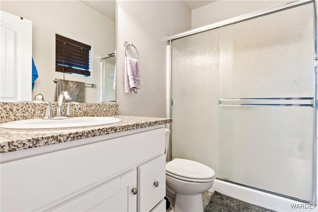 full bath featuring a stall shower, vanity, and toilet