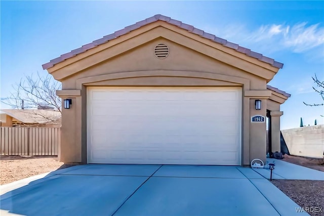 garage with concrete driveway and fence