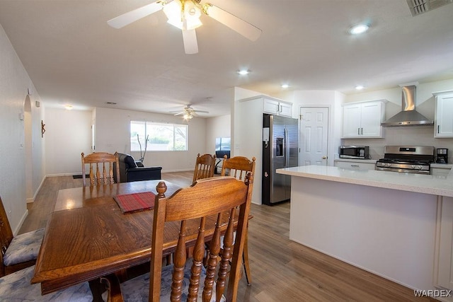 dining space with wood finished floors, baseboards, a ceiling fan, and visible vents