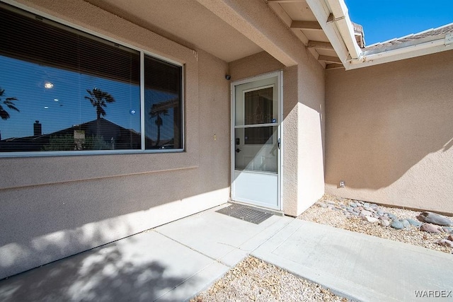 doorway to property featuring stucco siding and a patio