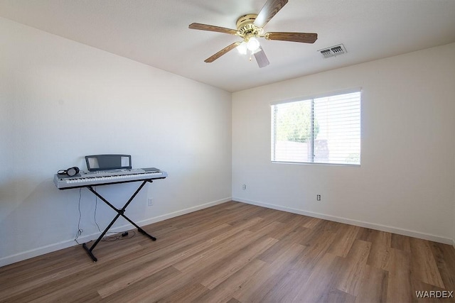 empty room with baseboards, wood finished floors, visible vents, and ceiling fan