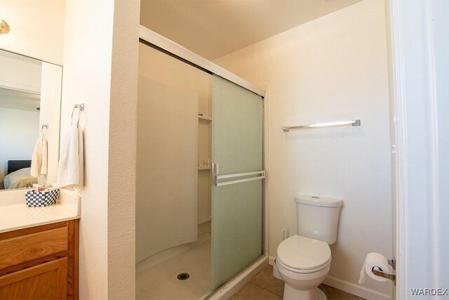 ensuite bathroom with ensuite bathroom, baseboards, a shower stall, and toilet