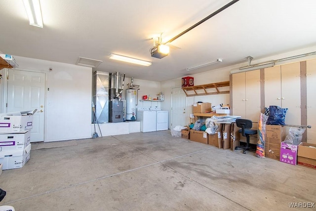 garage with gas water heater, washer and dryer, a garage door opener, and heating unit