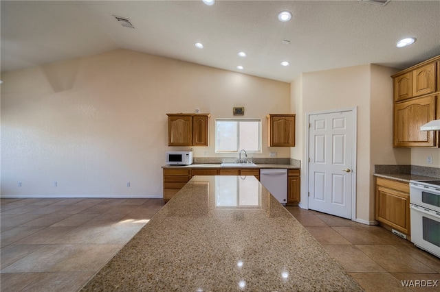 kitchen featuring white appliances, visible vents, lofted ceiling, light stone countertops, and a sink