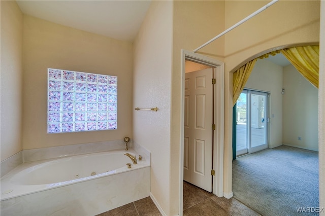 bathroom featuring tile patterned flooring, baseboards, and a bath