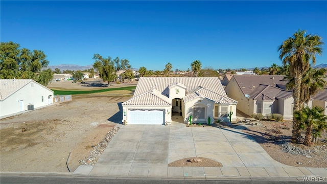 mediterranean / spanish home featuring a garage, concrete driveway, a tile roof, and stucco siding