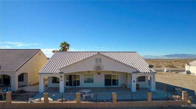 mediterranean / spanish house with fence private yard, stucco siding, a tiled roof, and a patio