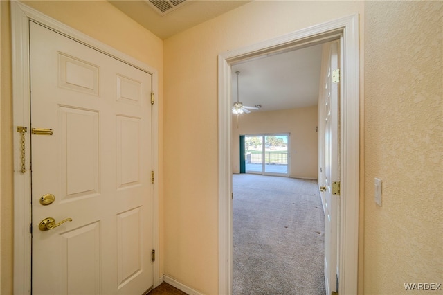 hall featuring baseboards, visible vents, and carpet flooring